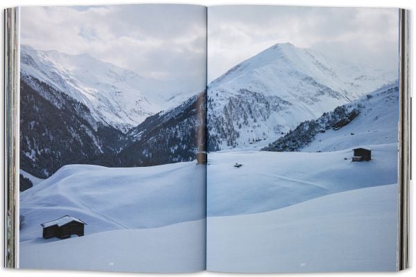 Book cover of Vrin: Home Through An Emigrant's Lens, with a person carrying two containers in snowy weather. Published by Scheidegger & Spiess.