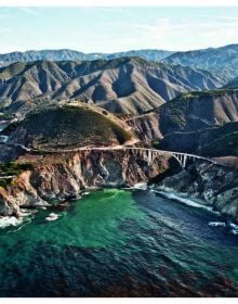 Aerial view of winding road in rocky mountain, near sea, on cover of 'Curves: USA - California', by Delius Klasing.