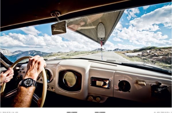 Cream Porsche 356 with small boat on roof rack traveling on road with mountains behind, on cover of 'Cars & Curves Vol.2', by Delius Klasing Verlag GmbH.