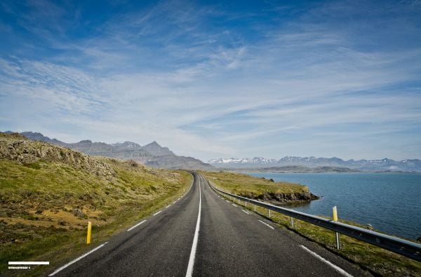 Mountainous landscape with lake and winding road in distance, on cover of 'Curves: Iceland, Volume 16', by Delius Klasing Verlag GmbH.