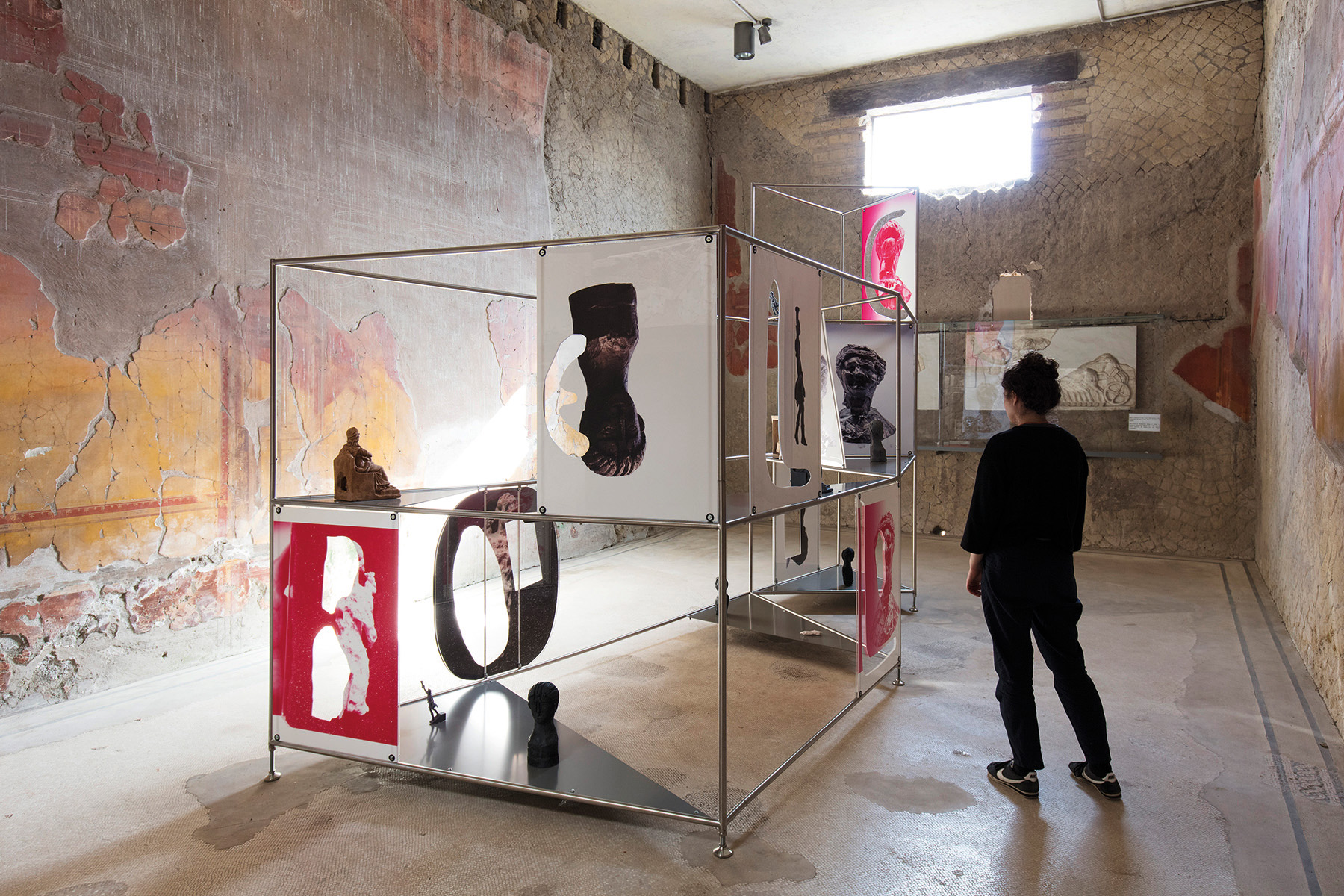 Installation wall with red, black, white, blue triangle shape patterns, Catrin Huber in white font to centre left