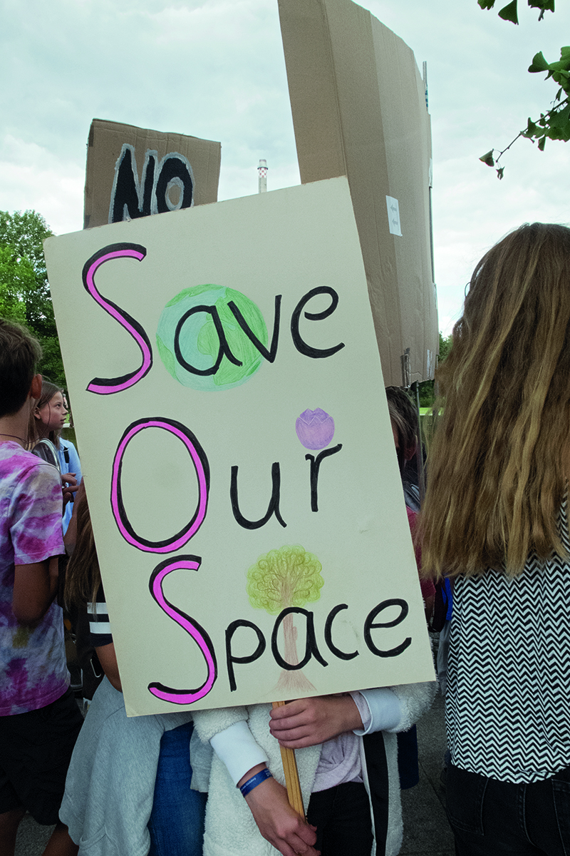 View of back of climate change protestors holding placards for Fridays for Future, WIR SIND HIER SIND LAUT FRIDAYS FOR FUTURE in red font across cover.