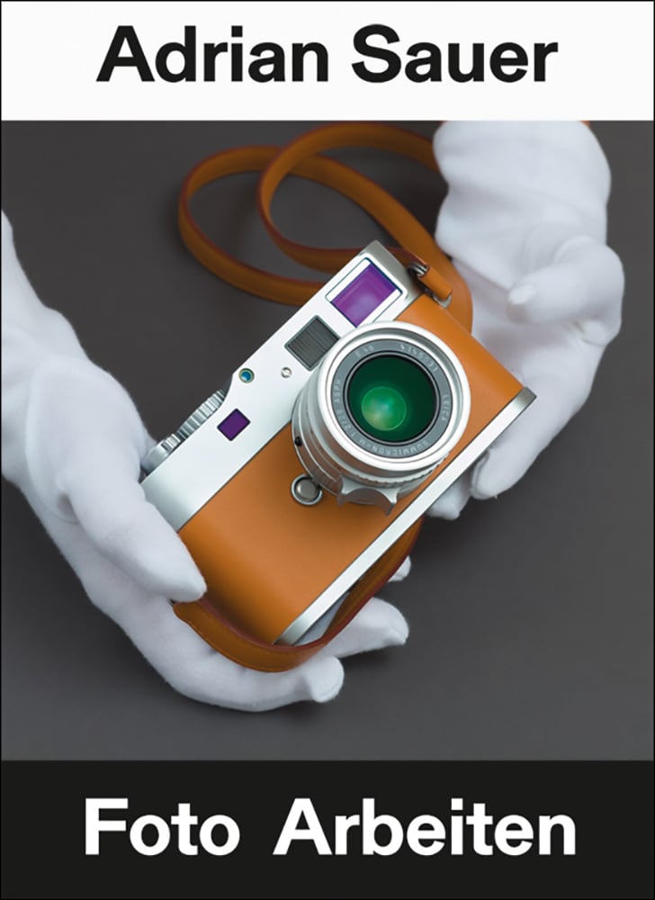 Book cover of Adrian Sauer: Foto Arbeiten / Photo Works, with a tan coloured compact SRL camera held by white gloved hands. Published by Kerber.