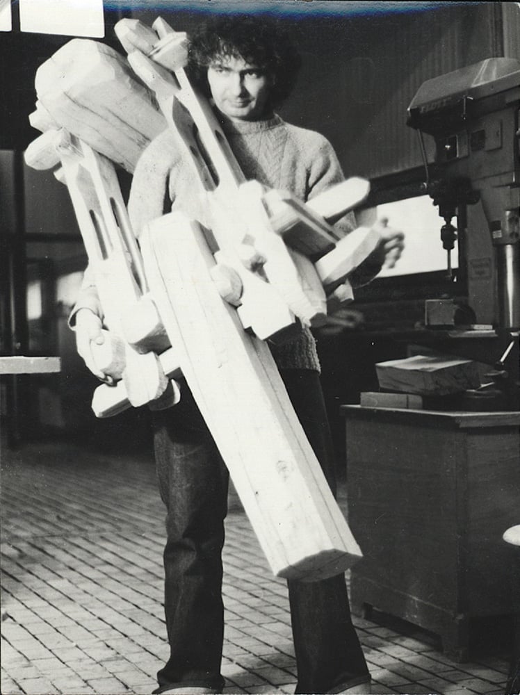 Book cover of Mihai Olos, with the artist in the studio, holding a large wooden sculpture. Published by Kerber.