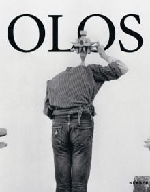 Book cover of Mihai Olos, with the artist in the studio, leaning forward, while holding a wooden object above his head. Published by Kerber.