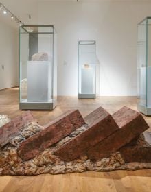 Close up image of textured grey concrete surface with deep dark crevice in centre and Sabine Groß Show Time in white font