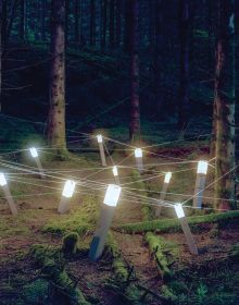 Light installation on wood structure, in a dark forest setting, Rune Guneriussen Lights go out in white font to left side, by Kerber.