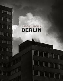 Brutalist style high rise in Berlin, person standing on top, under dark sky, JASON LANGER, BERLIN, in beige and black font above.