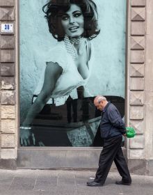 Book cover of Bella Italia: on beauty and ugliness. Christian Jungeblodt, with a tanned man in blue trunks walking past street lamp on the Italian seafront promenade at Bari. Published by Kerber.