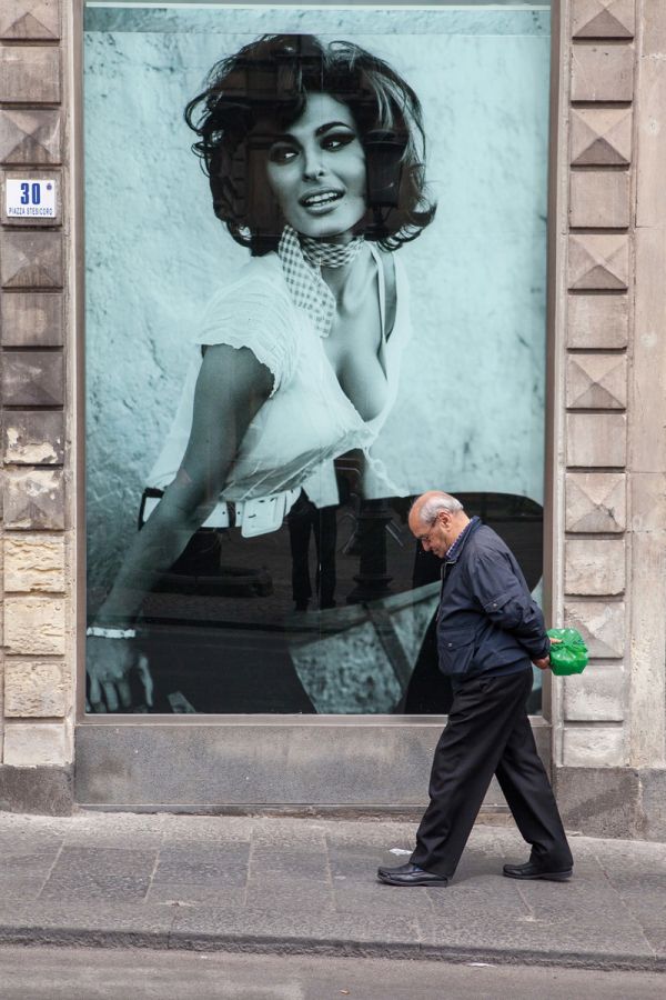 Book cover of Bella Italia: on beauty and ugliness. Christian Jungeblodt, with a tanned man in blue trunks walking past street lamp on the Italian seafront promenade at Bari. Published by Kerber.