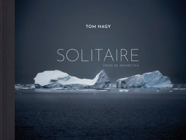 Book cover of Tom Nagy: SOLITAIRE: Faces of Antarctica, with two large icebergs floating on water in Antarctica. Published by Kerber.