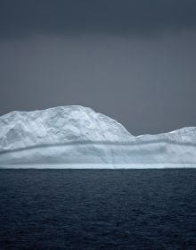 Two large icebergs floating on water in Antarctica, TOM NAGY, SOLITAIRE, in white font above.