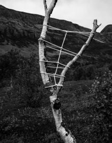 Large grey rock bound in rope, on coastal edge, on cover of 'Anna Reivilä, Nomad', by Kerber.