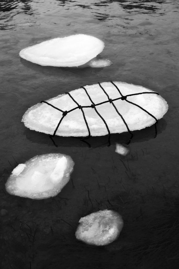 Book cover of Anna Reivilä, Nomad, with a large grey rock bound in rope, on coastal edge. Published by Kerber.