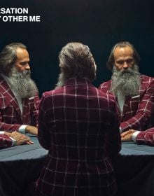 Landscape book cover of René Riis, Conversation with My Other Me, with mirrors creating five images of the same man with large grey beard, wearing a red and white checked jacket, sitting at table. Published by Kerber.