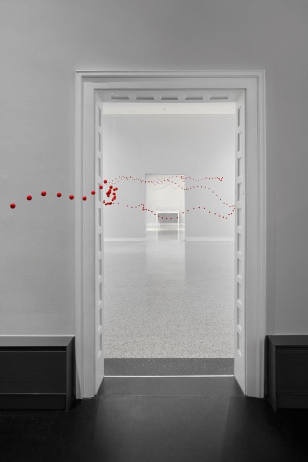 Book cover of Between One Line: Katharina Hinsberg & Monika Gryzmala, with an art installation of white wire and small red balls. Published by Kerber.