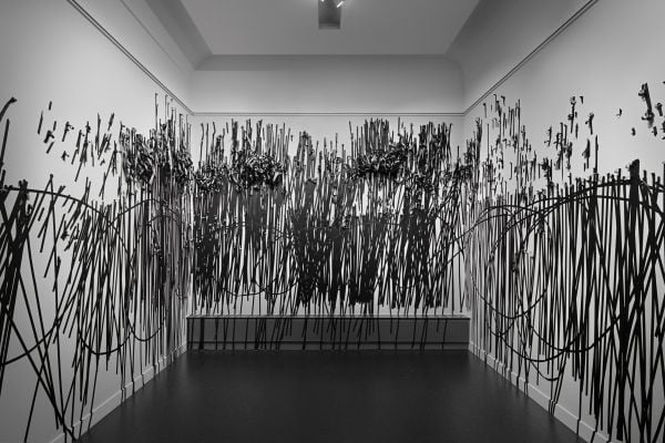 Book cover of Between One Line: Katharina Hinsberg & Monika Gryzmala, with an art installation of white wire and small red balls. Published by Kerber.