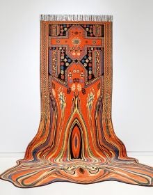 Book cover of Faig Ahmed, with a large, red textile rug suspended on white exhibition wall, with the black bottom half in shape of spilt liquid. Published by Kerber.