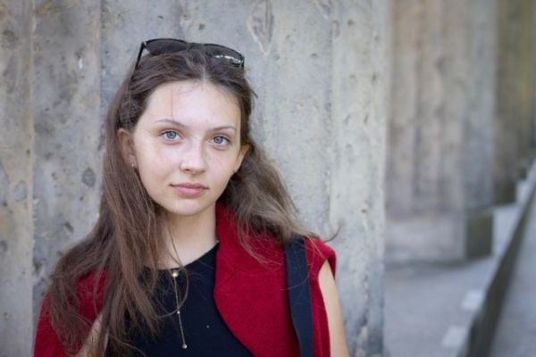 Book cover of Being Young: Portraits of Becoming; featuring a portrait of young woman with a septum piercing, wearing bold earrings and a pink scarf. Published by Kerber.