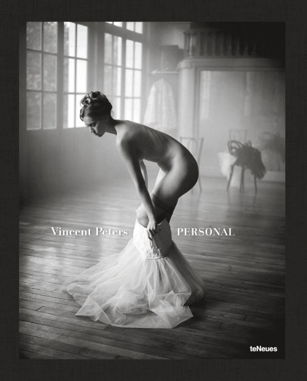 Nude white female model pulling on a white netted skirt, in studio space, Vincent Peters PERSONAL, in white font to lower left of centre cover.
