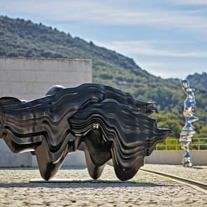 Tall curved wood sculptures in exhibition space, Anthony Cragg Endless Form in white font to upper left