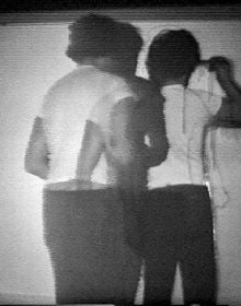 Photo montage of black and white shots of topless model, with black spray paint covering images below, Travaux/Works 1964-2013 in white font to bottom right.