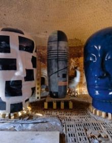 Ceramic glazed sculpture of head on low table, orange cover, Jun Kaneko The Space Between in white font to upper left.