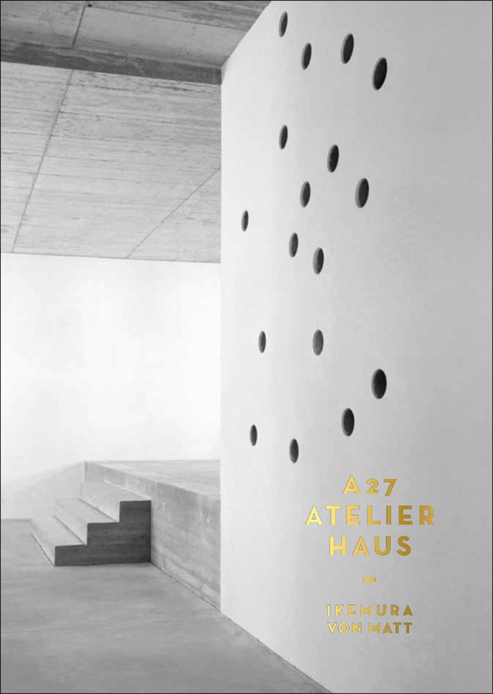 Off white concrete interior wall of building, with large holes, 3 steps, A 27 ATELIERHAUS in gold font to lower right