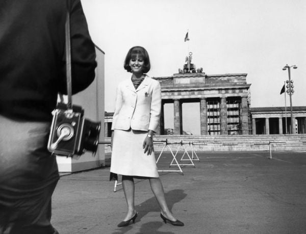 Book cover of Between the Films, A Photo History of the Berlinale, with James Stewart in suit and trilby, standing near water fountains with high-rise behind. Published by Verlag Kettler.