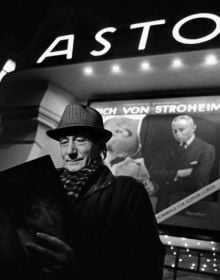 Book cover of Between the Films, A Photo History of the Berlinale, with James Stewart in suit and trilby, standing near water fountains with high-rise behind. Published by Verlag Kettler.