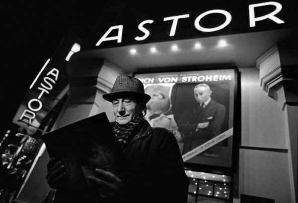 Book cover of Between the Films, A Photo History of the Berlinale, with James Stewart in suit and trilby, standing near water fountains with high-rise behind. Published by Verlag Kettler.