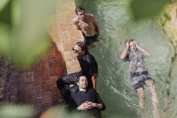 Cream book cover of My Friends Got Famous, with red and white striped flip flop floating on top of in blue swimming pool water. Published by Verlag Kettler.