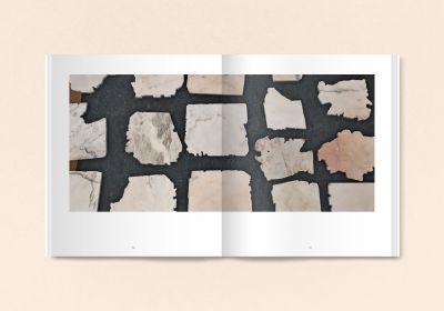 Black book cover of Talya Lubinsky, Marble Dust, with a fragment of white marble mottled with grey. Published by Verlag Kettler.