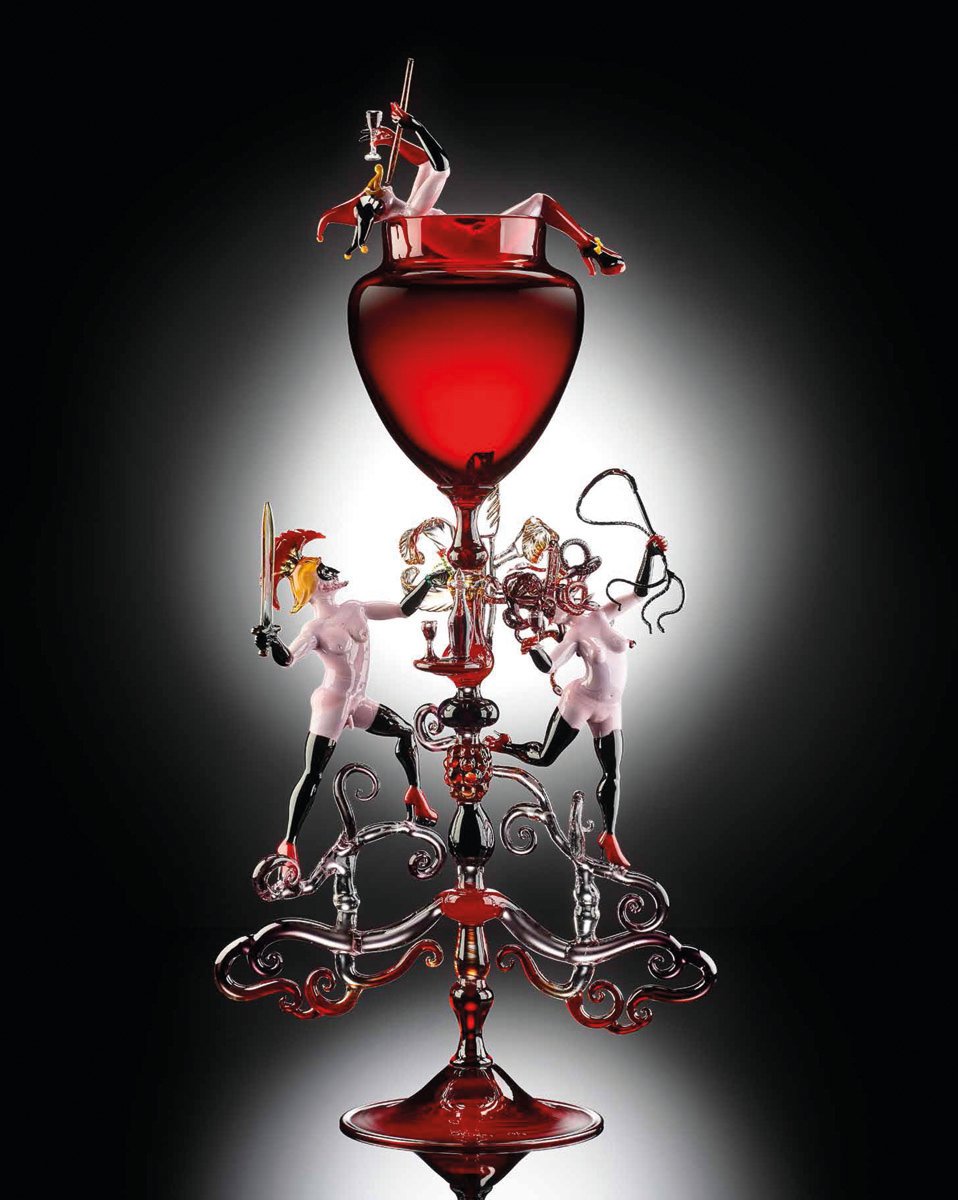 Blood red glass bowl, glass figure in red suit and mask with black horns, exposed breasts and platform boots, Lucio Bubacco erotics in white font