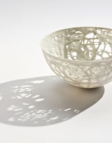 Delicate cream filigree porcelain bowl, on white cover, Barbel Thoelke Porzellan in white and black font below
