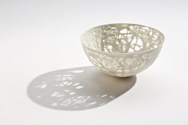 Delicate cream filigree porcelain bowl, on white cover, Barbel Thoelke Porzellan in white and black font below