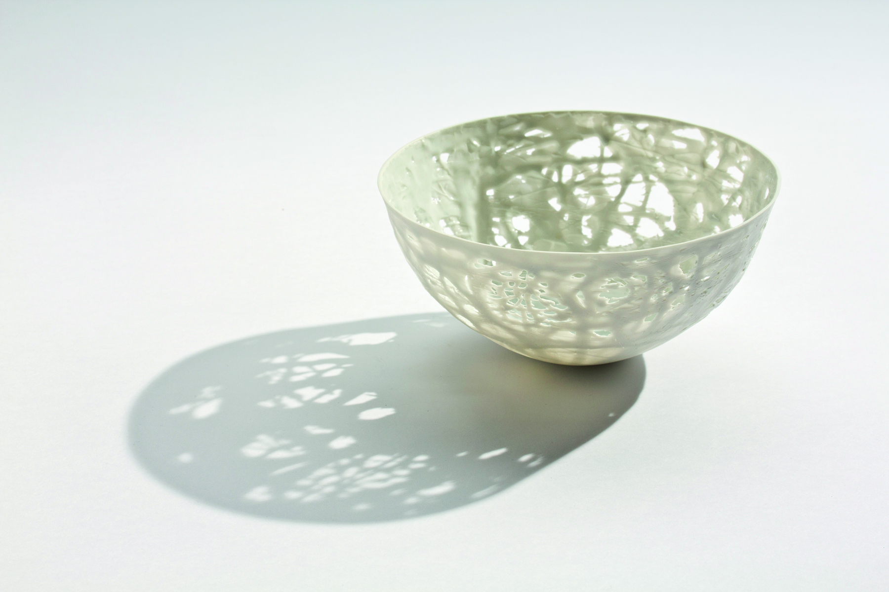 Delicate cream filigree porcelain bowl, on white cover, Barbel Thoelke Porzellan in white and black font below