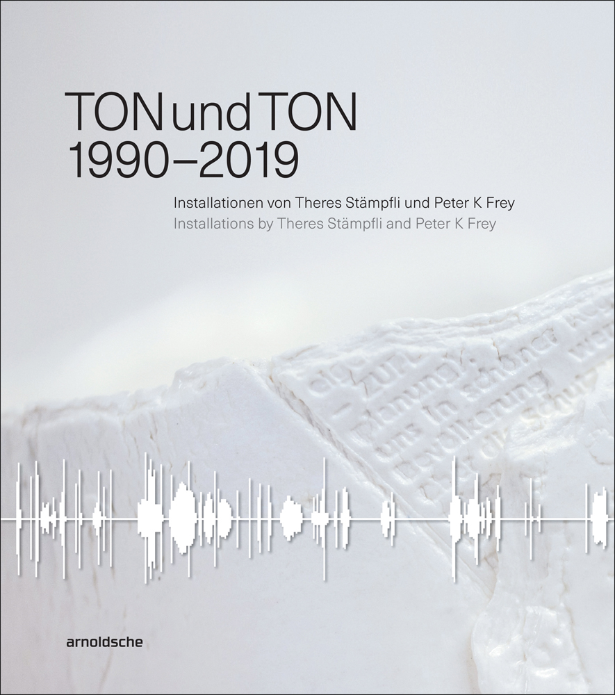 White ceramic shape with embossed text to surface, white sound waves across lower edge, TONundTON 1990-2019 in black font above.
