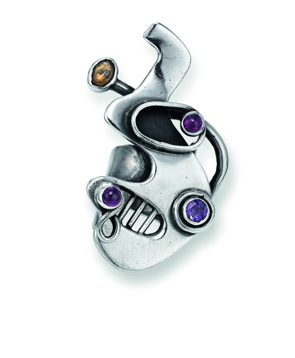 Organic shaped silver metal jeweller with coloured stones, off-white background, SAM KRAMER JEWELER ON THE EDGE in black font above.