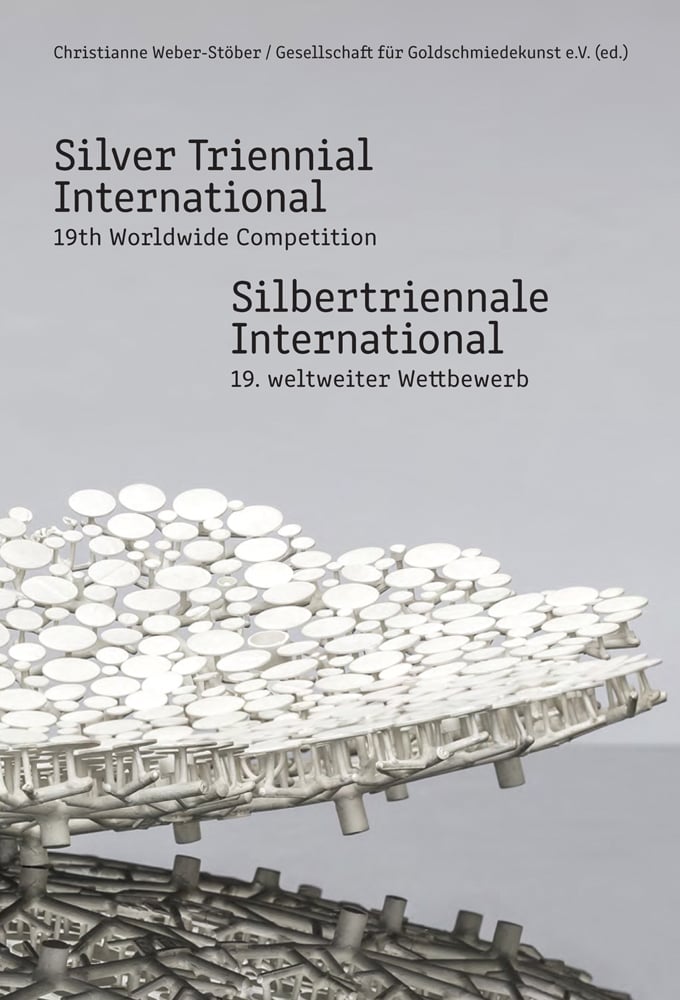 Silver metal sculpture made of small stemmed discs, pale grey cover, Silver Triennial International 19th Worldwide Competition in black font above.