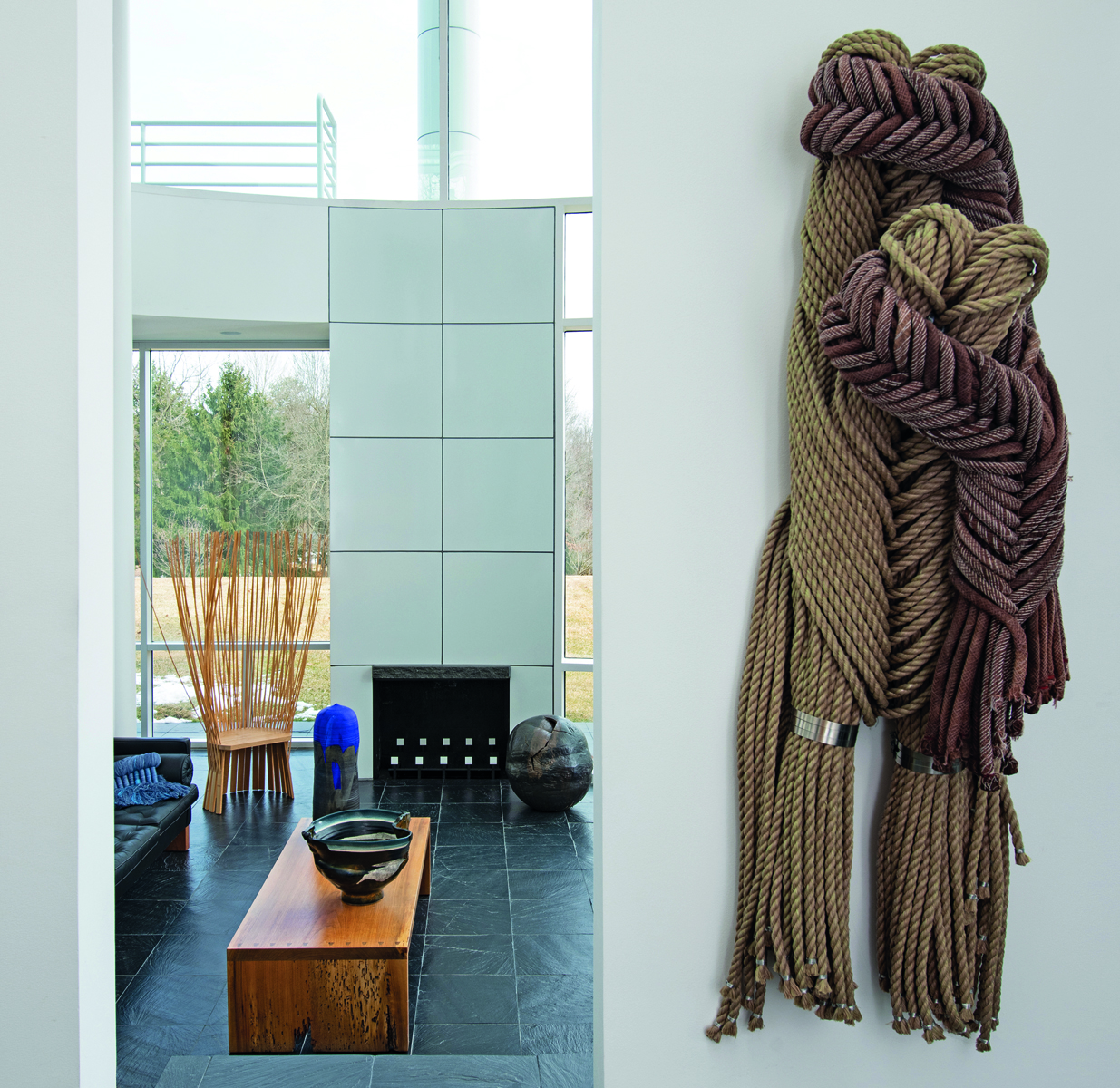 Sculpture of bird made from wood and fibres, on white windowsill looking out, The Grotta Home by Richard Meier in white font to upper left.