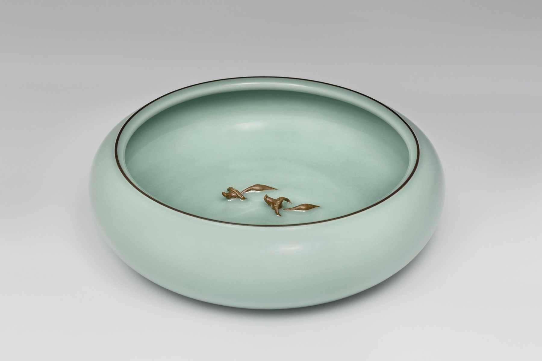 Delicate mint green crackle glazed porcelain bowl, grey background, Seladon im Augenmaerk in white font above.