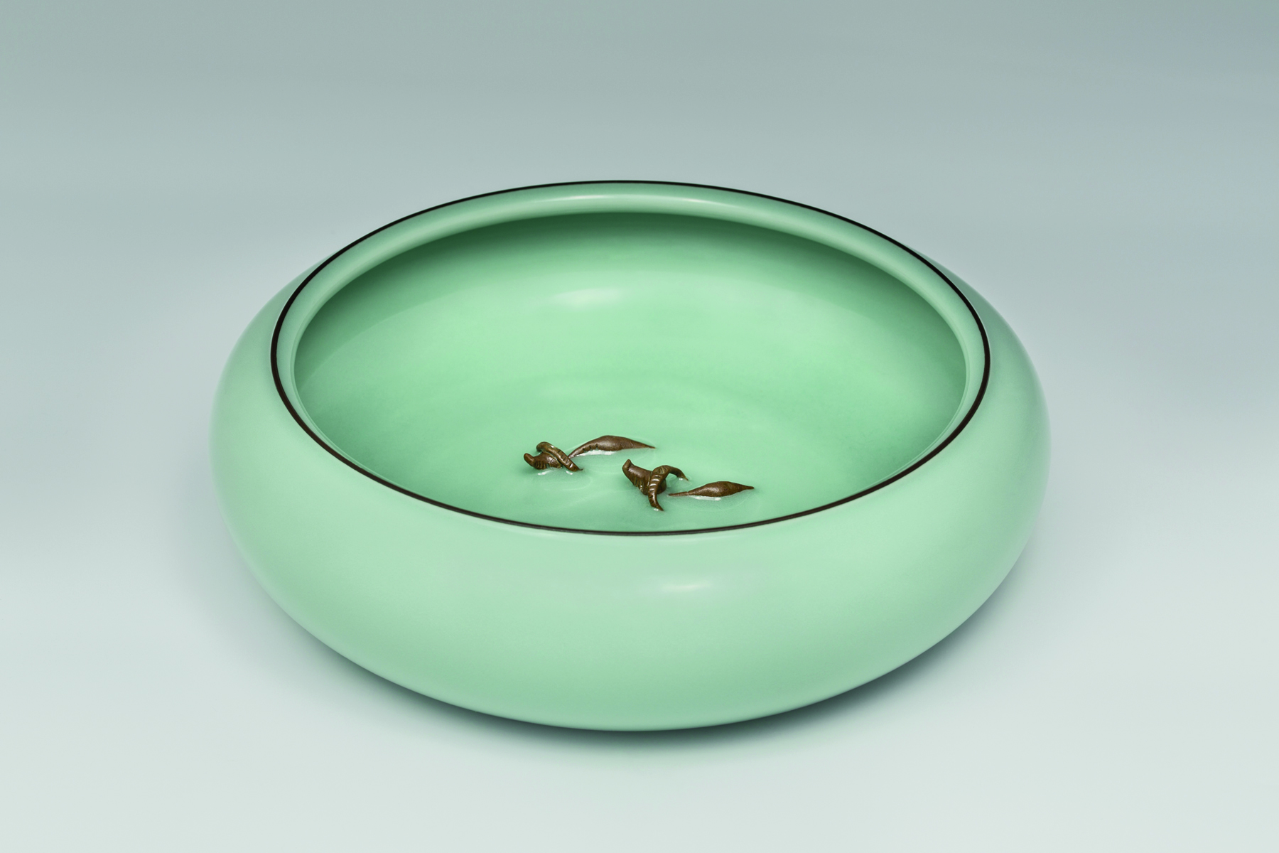 Delicate mint green crackle glazed porcelain bowl, grey background, Seladon im Augenmaerk in white font above.