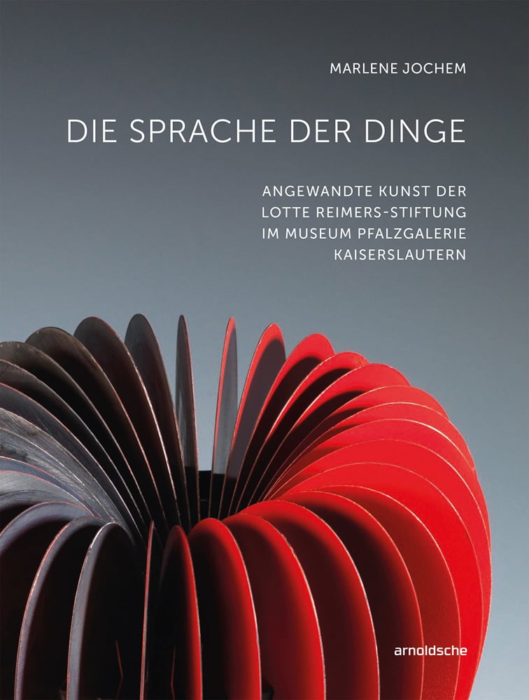 Apple like sculpture in red sheets of material, grey cover, DIE SPRACHE DER DINGE in white font above.