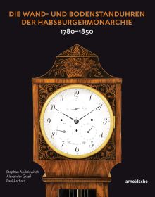 White lock face with gold mechanism, on black cover of 'Die Wand- und Bodenstanduhren der Habsburgermonarchie, 1780–1850', by Arnoldsche Art Publishers.