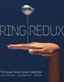 Dark-skinned hand with silver ring with long stem and flower, on index finger, on cover of 'Ring Redux, The Susan Grant Lewin Collection', by Arnoldsche Art Publishers.