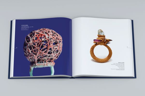 Dark-skinned hand with silver ring with long stem and flower, on index finger, on cover of 'Ring Redux, The Susan Grant Lewin Collection', by Arnoldsche Art Publishers.