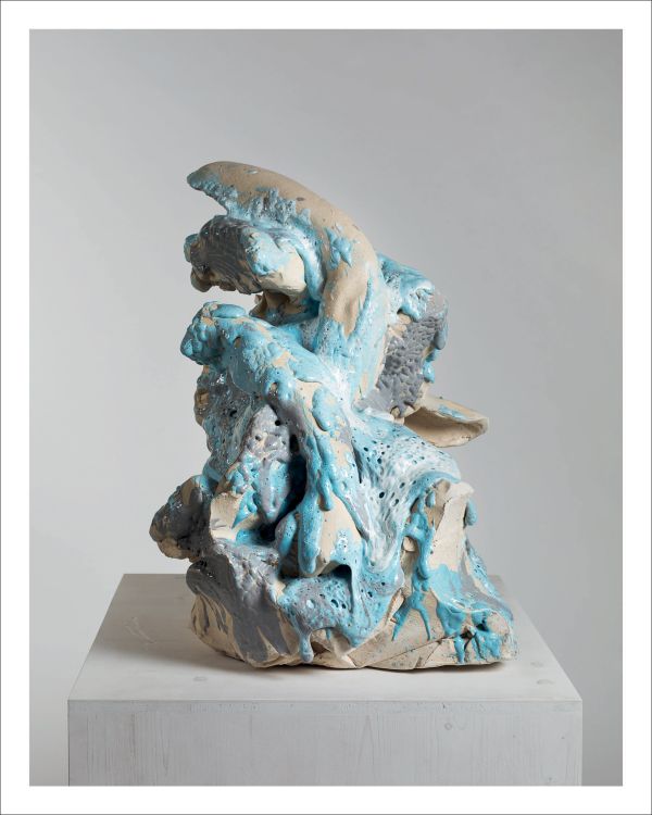 Deformed head like sculpture with ears glazed in white and pink sitting on fabric covered box, on cover of 'Erwin Wurm, Dissolution', by Arnoldsche Art Publishers.