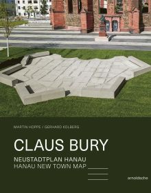 Geometric granite sculpture of map embedded in green grass, on cover of 'Claus Bury, Hanau New Town Map', by Arnoldsche Art Publishers.