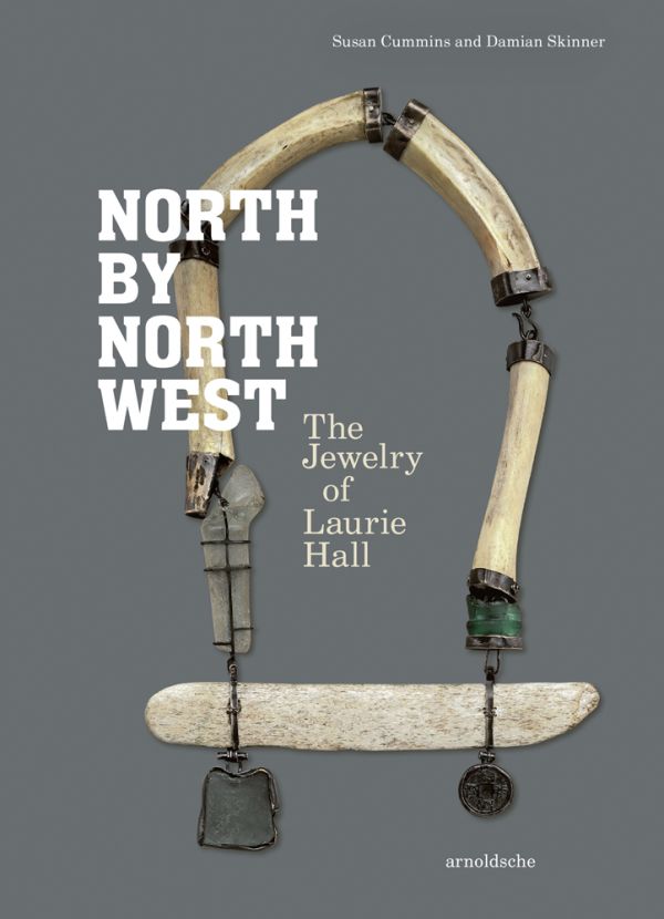 Book cover of North by Northwest, The Jewelry of Laurie Hall, with a jewelry piece made of wooden tube shapes, and dark metal pendants. Published by Arnoldsche Art Publishers.